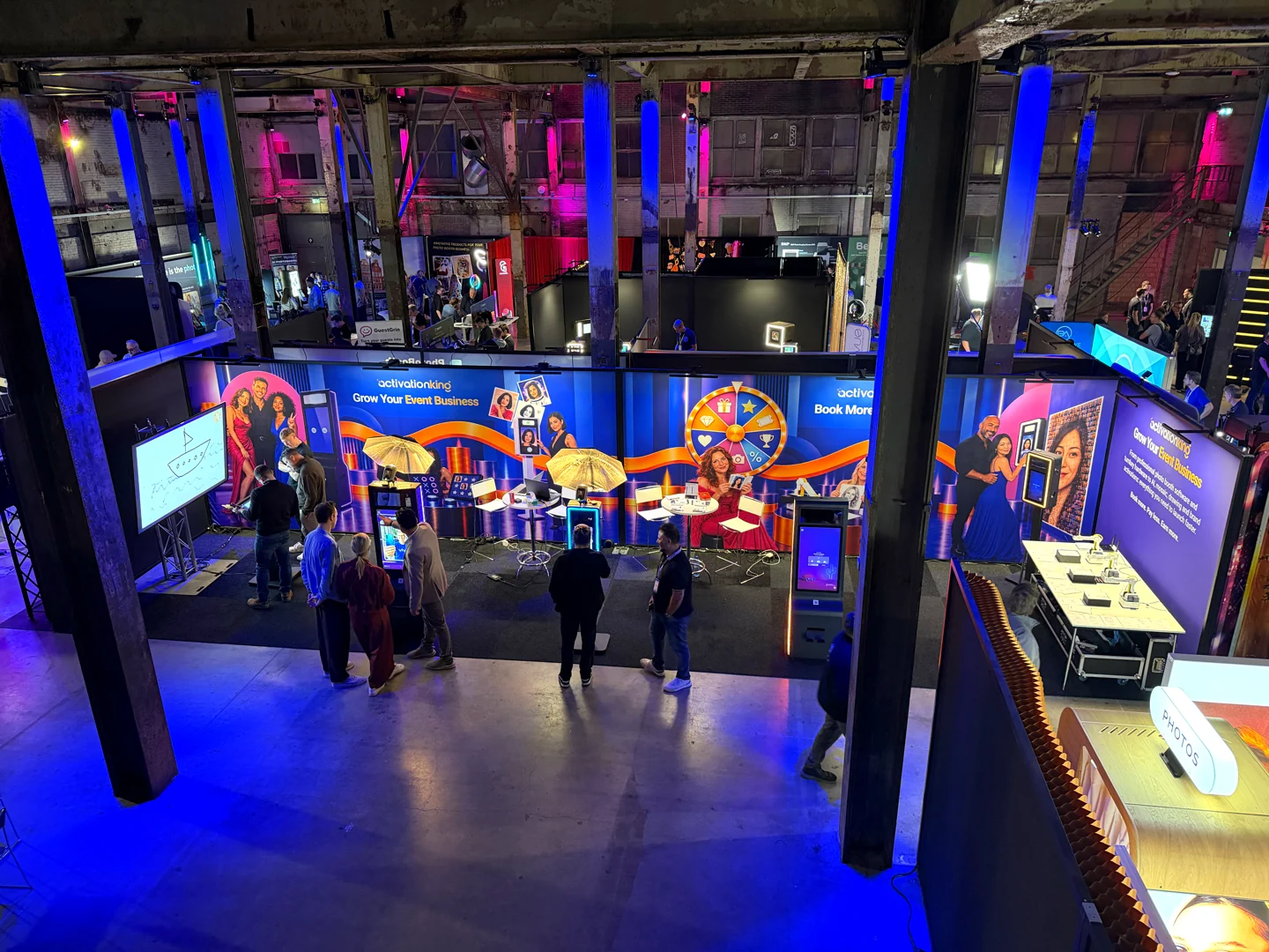 PBX Europe 2026’da Activation King standındaki fotoğraf kabinleri, interaktif ekranlar ve robot masasının yukarıdan görünümü.